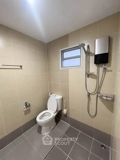 Modern bathroom with beige tiles, shower, and toilet in a sleek real estate property.