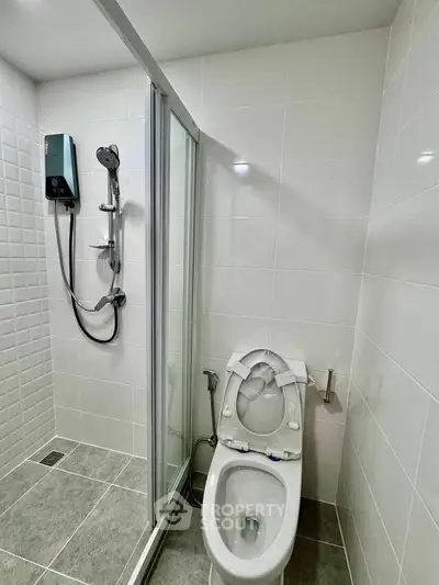 Modern bathroom with shower and toilet in sleek white tile design.
