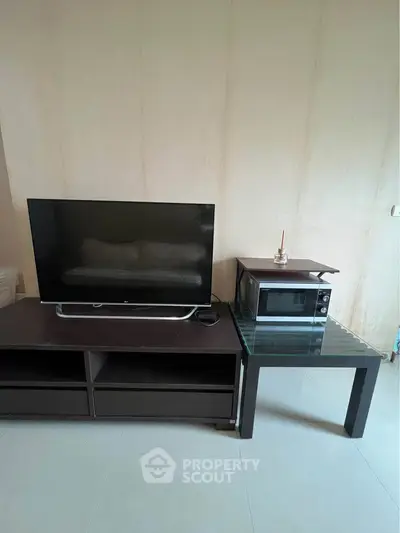 Modern living room with sleek TV and microwave on stylish furniture.