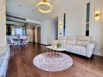 Spacious modern living room with elegant decor and open dining area, featuring hardwood floors and stylish lighting.
