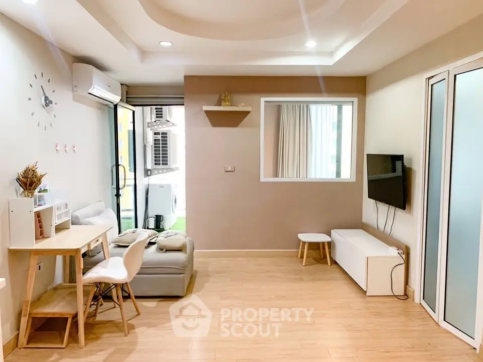 Modern living room with stylish decor and natural light, featuring a cozy seating area and wall-mounted TV.