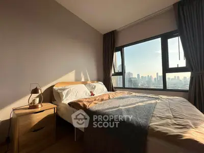 Cozy bedroom with city view, featuring a comfortable bed and natural light through large windows.