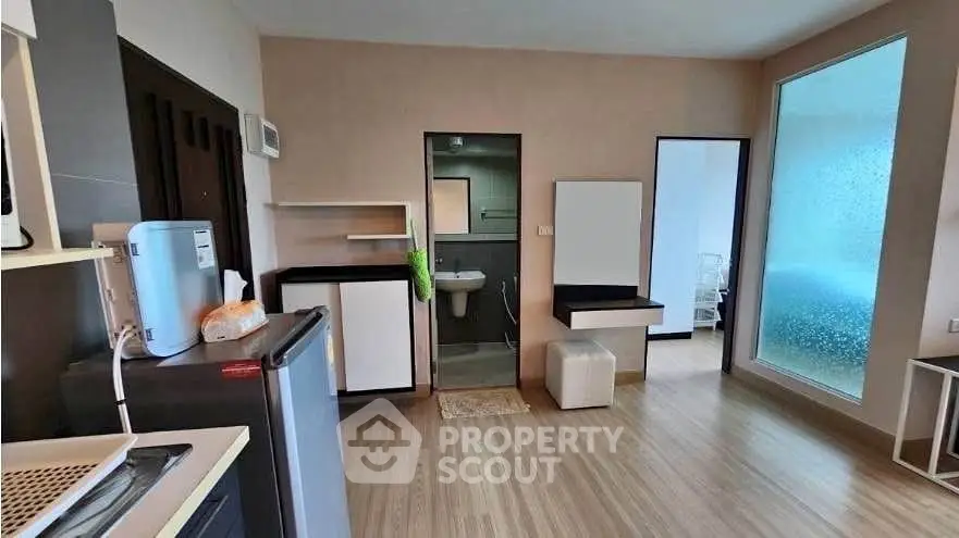 Modern studio apartment with kitchenette and bathroom, featuring sleek design and wooden flooring.