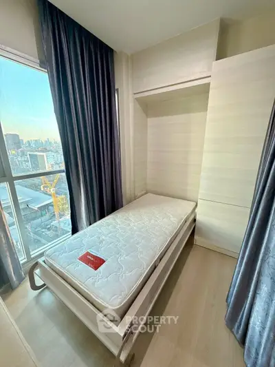 Cozy bedroom with single bed and city view, perfect for urban living.