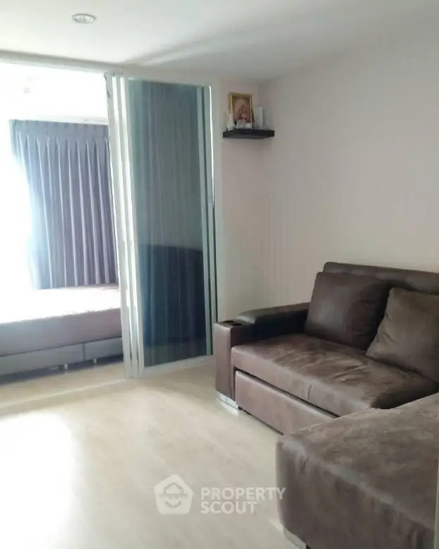 Modern living room with sleek sliding glass door and cozy brown sofa, perfect for urban living.