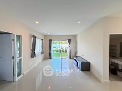 Spacious living room with large windows and garden view, perfect for family gatherings.