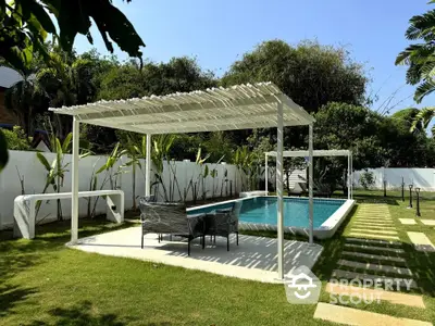 Luxurious outdoor pool area with stylish pergola and lush greenery, perfect for relaxation and entertainment.