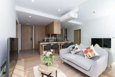 Modern living room with open kitchen, stylish decor, and cozy seating area.