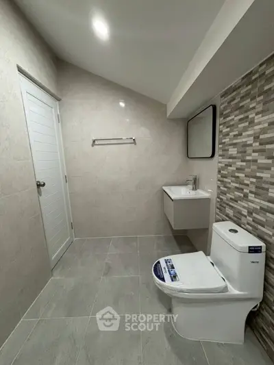 Modern bathroom with sleek design, featuring a wall-mounted sink and contemporary toilet.