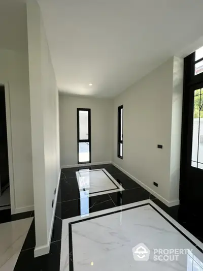 Modern minimalist hallway with sleek black and white marble flooring, large windows, and elegant design.