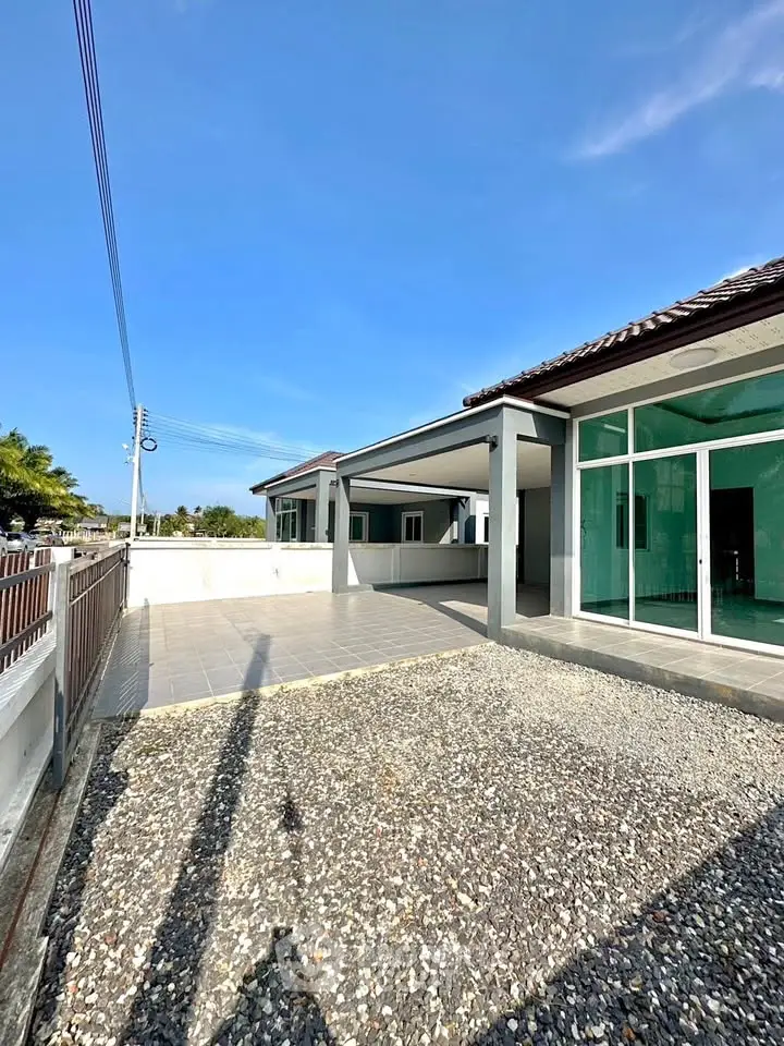 Spacious modern home exterior with large driveway and clear blue sky.