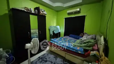 Cozy bedroom with vibrant green walls, air conditioning, and ample storage space.