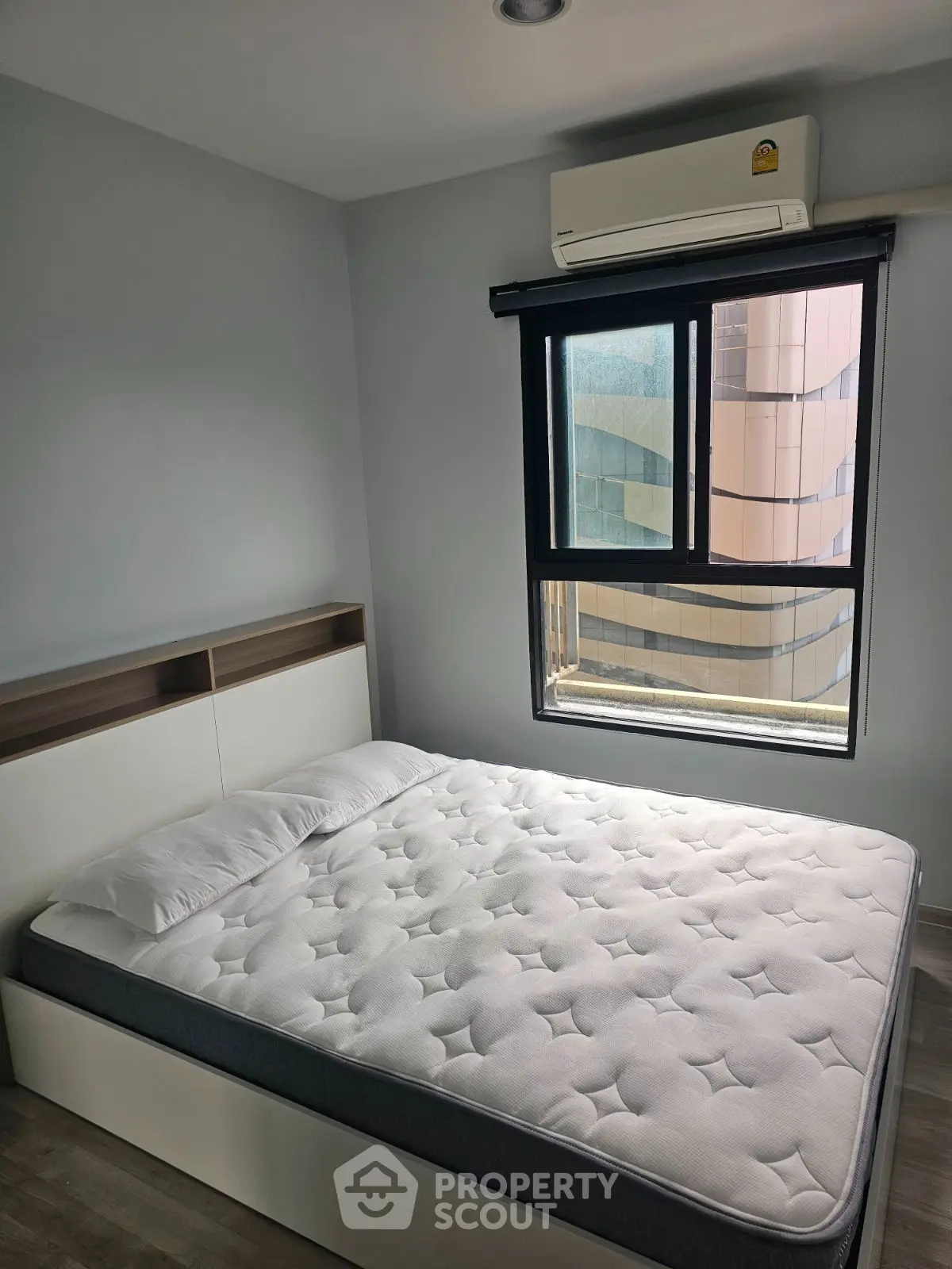 Modern bedroom with large window and air conditioning, featuring a comfortable bed and sleek design.