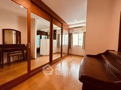 Spacious bedroom with elegant wooden flooring and large mirrored closet doors.