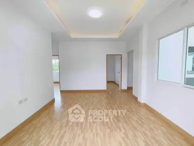 Spacious empty room with wooden flooring and bright natural light, ideal for customization.