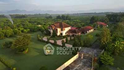 Stunning aerial view of luxurious estate with lush gardens and scenic mountain backdrop.