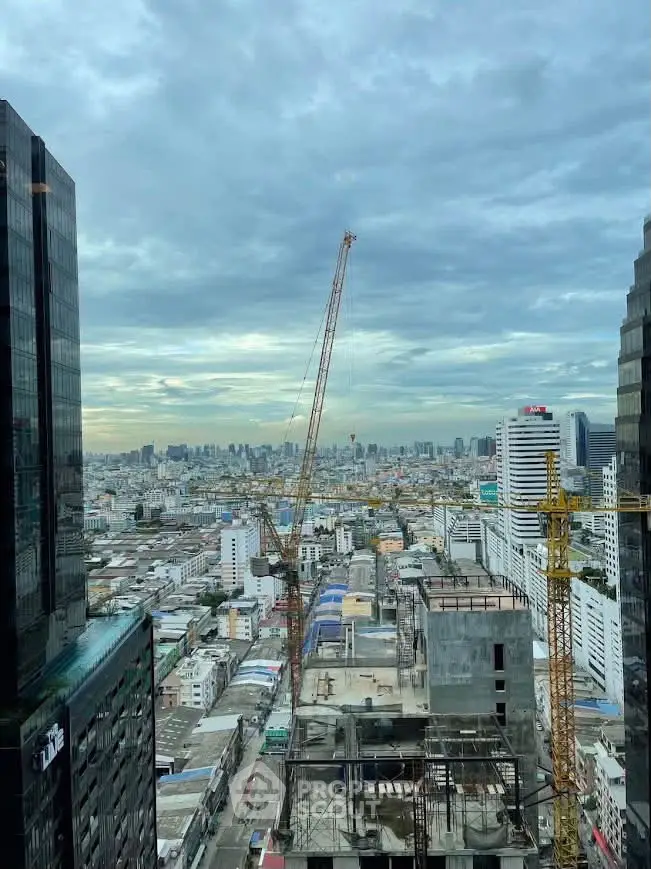 Stunning cityscape view from high-rise building with construction cranes and urban skyline.