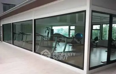 Modern gym with large windows and fitness equipment in a residential building.