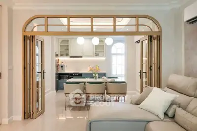 Elegant open-plan living room with modern kitchen and stylish dining area, featuring chic lighting and cozy seating.