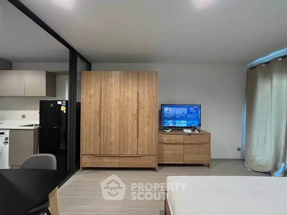 Modern studio apartment with sleek wooden furniture and open layout, featuring a cozy living area and kitchen.