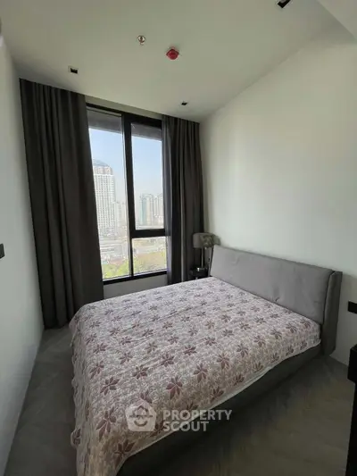 Modern bedroom with large window offering city view, featuring stylish decor and cozy ambiance.