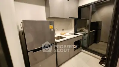 Modern kitchen with sleek cabinetry and stainless steel fridge in a compact layout.