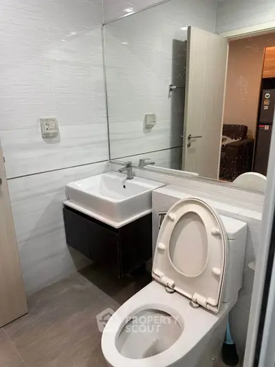 Modern bathroom with sleek fixtures and large mirror in contemporary apartment.