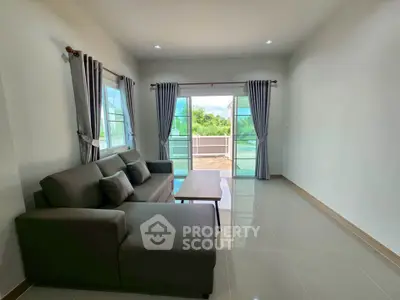 Spacious living room with modern sofa and large windows opening to a scenic balcony view.