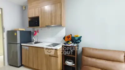 Modern compact kitchen with wooden cabinets and cozy seating area in a stylish apartment.