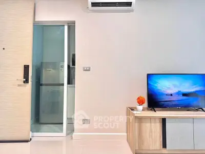 Modern living room with sleek TV setup and air conditioning, adjacent to a compact kitchen area.