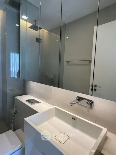 Modern bathroom with sleek fixtures and large mirror in a contemporary apartment.