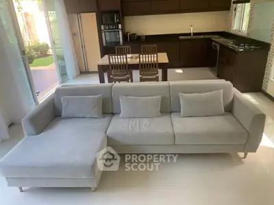 Spacious modern living room with sleek kitchen and garden view, featuring a stylish gray sectional sofa.