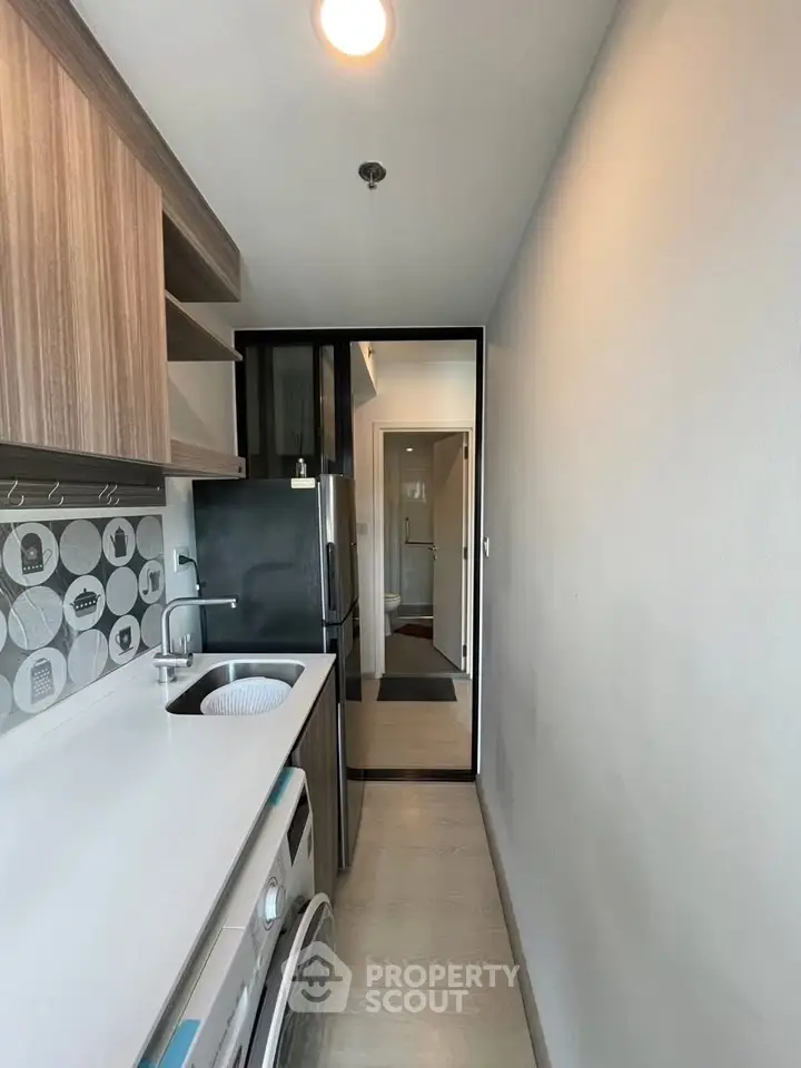 Modern compact kitchen with sleek design and washing machine, ideal for urban living.