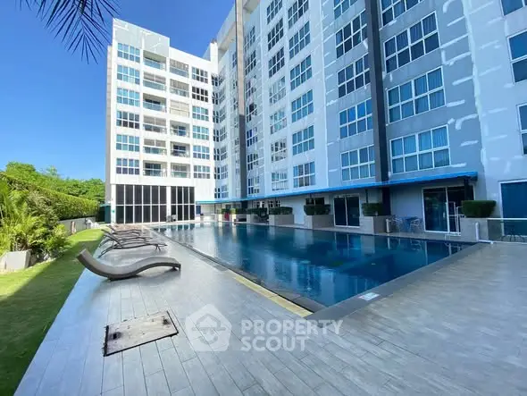 Modern condominium with poolside view and sleek architecture under clear blue sky.