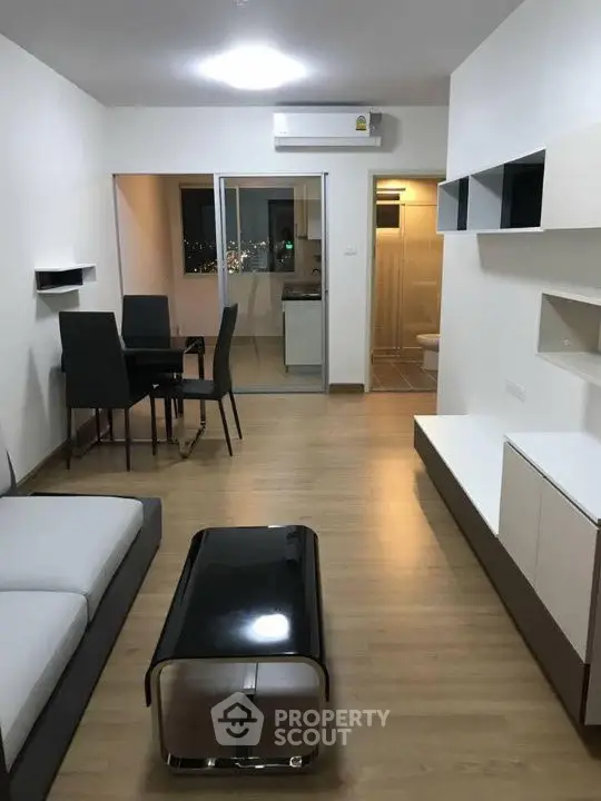 Modern living room with sleek furniture and open layout, featuring a dining area and air conditioning.