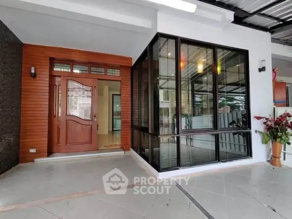 Modern home entrance with stylish wooden door and large glass windows, featuring sleek tile flooring.