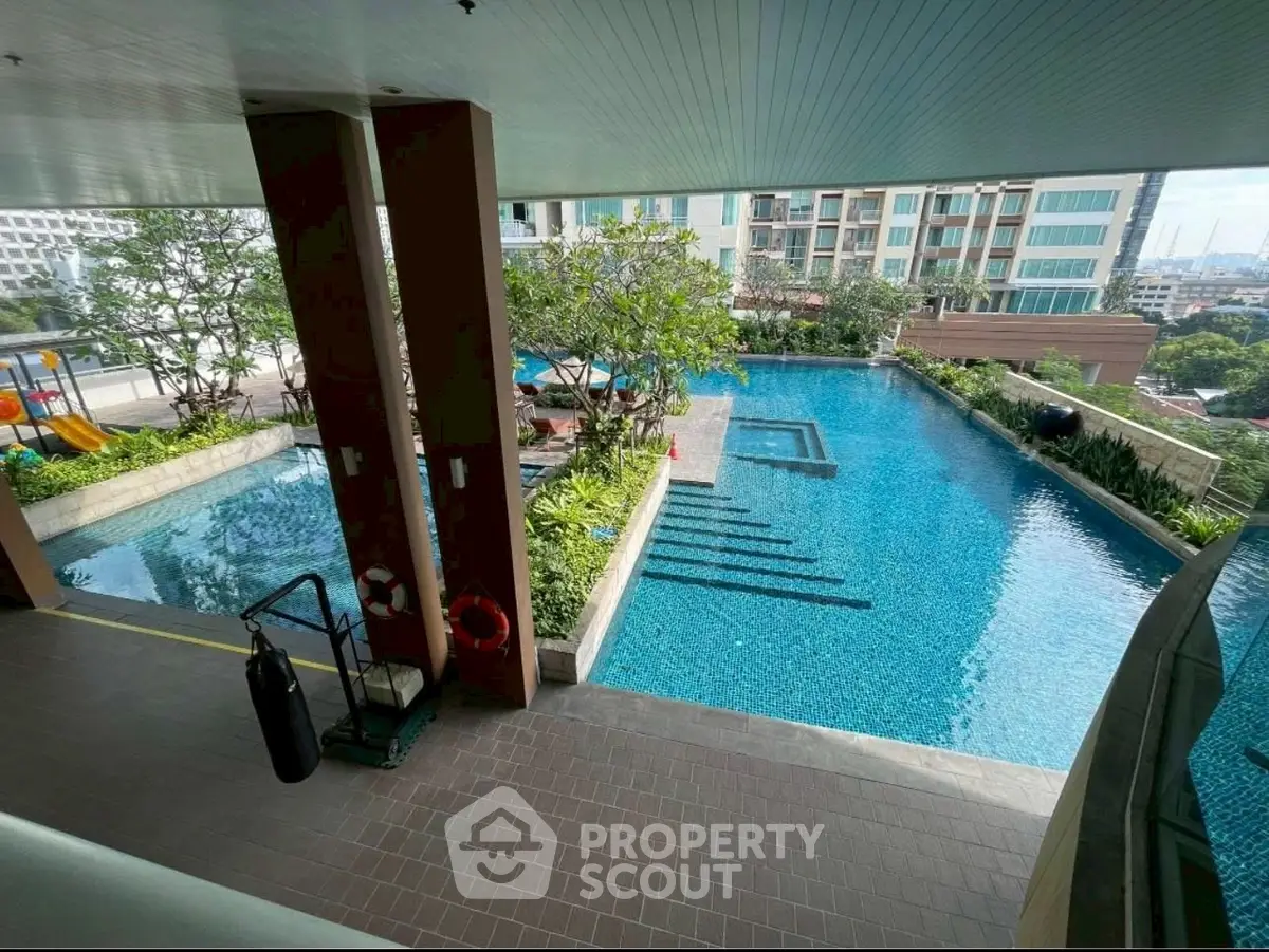 Luxurious condominium pool area with stunning city views and lush greenery.