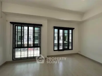 Spacious empty room with large windows and modern flooring, perfect for customization.