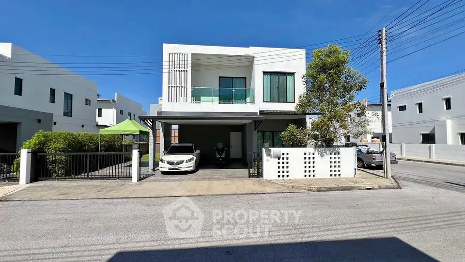 Modern two-story house with carport and lush greenery in a serene neighborhood.