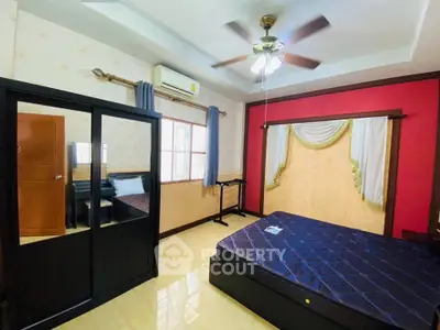 Spacious bedroom with modern furnishings and ceiling fan, featuring ample natural light and elegant decor.