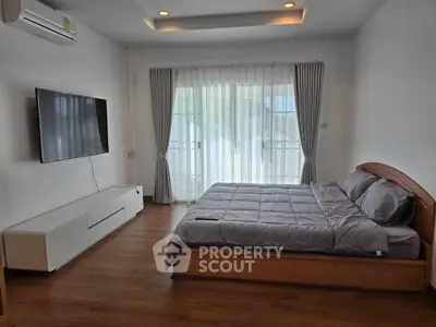 Spacious bedroom with modern decor and large window for natural light