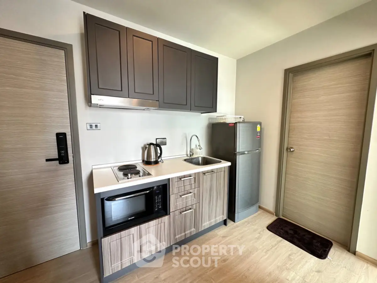 Modern compact kitchen with sleek cabinetry and stainless steel appliances in a cozy apartment.