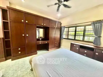 Spacious bedroom with built-in wooden wardrobes and large windows for natural light.