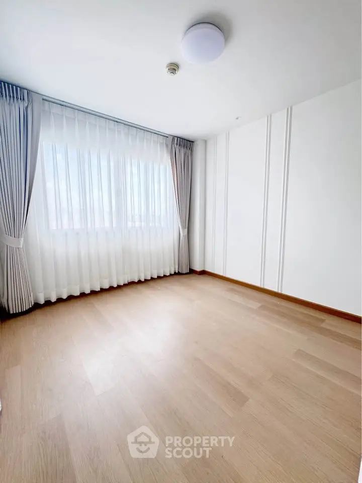 Spacious empty room with large window and elegant curtains, perfect for customization.