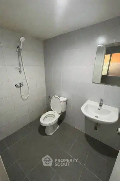 Modern minimalist bathroom with shower, toilet, and sink in neutral tones.