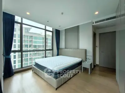 Spacious modern bedroom with large windows and elegant decor in a high-rise building.