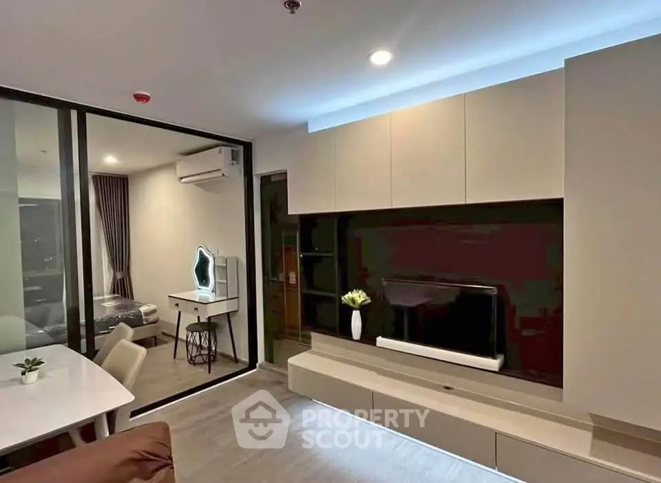 Modern living room with sleek built-in entertainment unit and view into stylish bedroom.