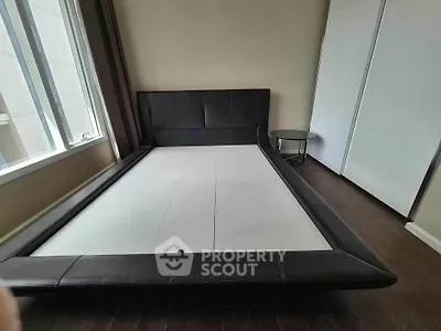 Spacious bedroom with modern bed frame and large window for natural light.