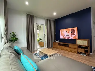 Modern living room with stylish decor and large sectional sofa, featuring a sleek entertainment center and vibrant accents.