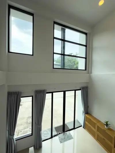 Spacious modern living room with high ceilings and large windows offering abundant natural light.